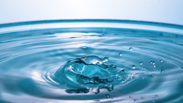 Water splash close-up. Drop of water. Blue water drop. Falling blue water surface with splash and air bubbles