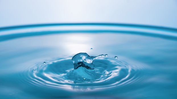 Water splash close-up. Drop of water. Blue water drop. Falling blue water surface with splash and air bubbles