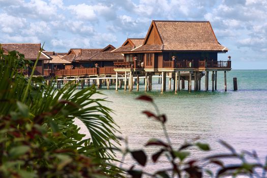 Wooden cottages, bungalows on clear blue water waiting for tourists in tropical oceans 