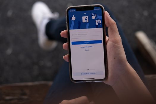 CHIANG MAI, THAILAND - JUL 16, 2019: Facebook social media app logo on log-in, sign-up registration page on mobile app screen on iPhone X (10) in person's hand working on e-commerce shopping business
