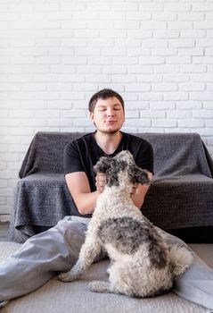 Stay home. Pet care. Young funny man enjoying his time together with his bichon frise dog. Copy space