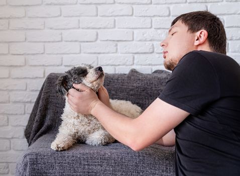 Stay home. Pet care. Young funny man enjoying his time together with his bichon frise dog. Copy space