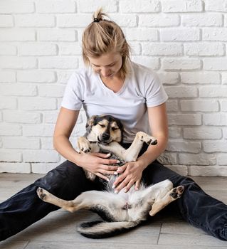 Stay home. Pet care. Togetherness concept. Blond caucasian woman patting her dog at home