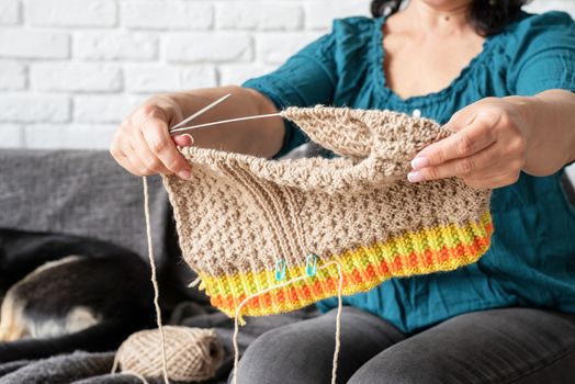 Stay home. Smiling middle aged woman enjoying being at home and knitting sitting on the sofa