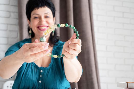 Beautiful smiling middle aged woman admiring the jewel necklace. Copy space. Selective focus