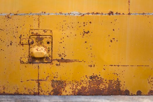 rusted yellow bus board with small hatch closeup with selective focus