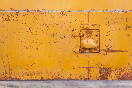 rusted yellow bus board with small hatch closeup with selective focus