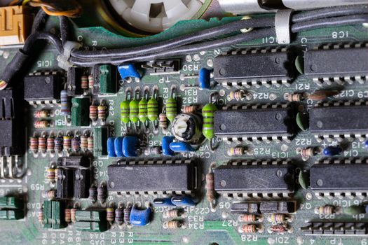 background of old electronic circuit board closeup in dark colors with dust and selective focus