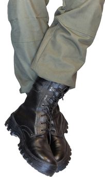 Crossed legs in army khaki pants and military black boots isolated on white background