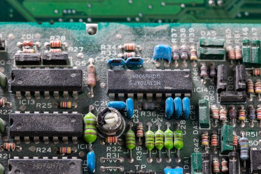 background of old electronic circuit board closeup in dark colors with dust and selective focus