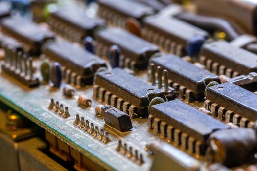 background of old electronic circuit board closeup in dark colors with dust and selective focus