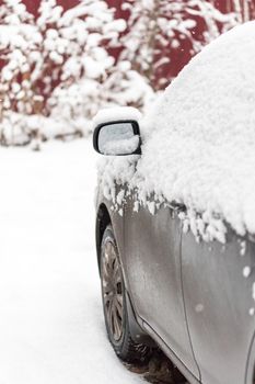 Dirty car covered by thick snow layer with selective focus.