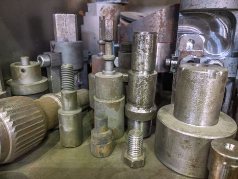 A lot of old rusted machining stock holders dark industrial background with selective focus.