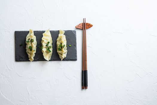 Kimchi dumplings meat dumplings on black stone plate over white textured background top view space for text nobody.