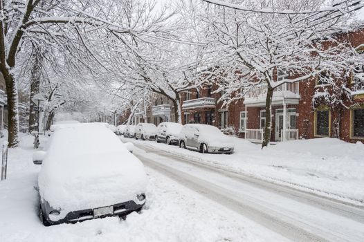 City street and cars covered in snow during winter storm in Montreal, Canada