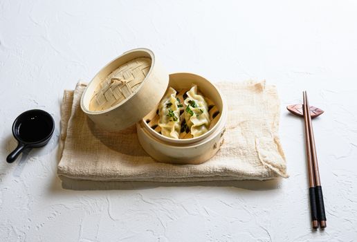 Chinese snacks. chinese steamed dumpling. Chinese Traditional cuisine in wooden steamer, dumplings snack , on linen cloth served on white textured stone tableside view.