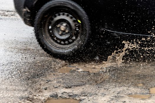 Car driving through a pothole with splashes of water, Montreal, Canada.