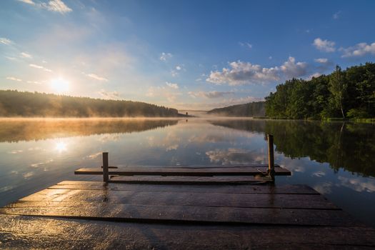 foggy summer sunrise over the river with a wooden pier