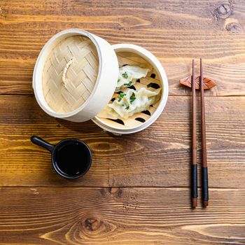 Japanese gyoza or dumplings snack with soy sauce in wooden steamer on wood japan table top view