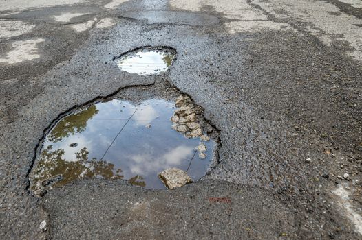Large rounded pothole filled with water in Montreal
