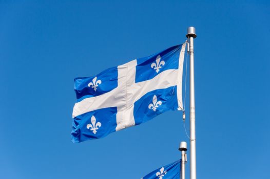 Quebec Flag waving in the wind against blue sky in Quebec City.