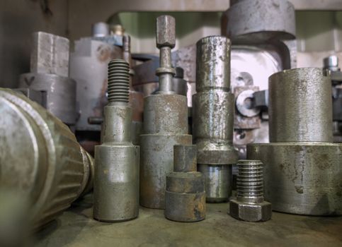 A lot of old rusted machining stock holders dark industrial background with selective focus.