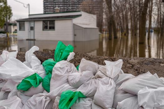 House submerged by water during floods, with sand bags in the foreground.