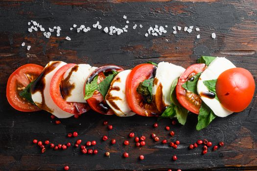 Concept Top view of fresh italian caprese salad with sliced tomatoes, mozzarella, green basil sliced on old kitchen table top view horizontal.