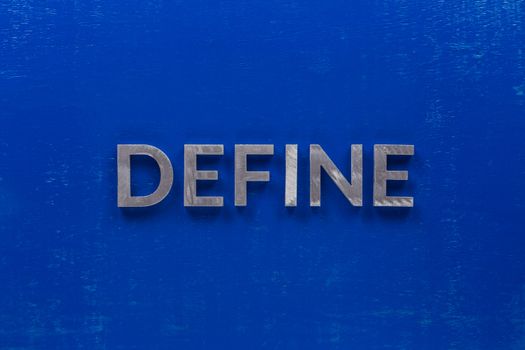 the word define laid on blue painted board with thick silver metal capital letters.