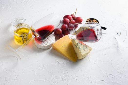 Two red wine glass with Cheese appetizer selection or whine snack set. Variety of cheese, grapes, pecan nuts side view space for text.