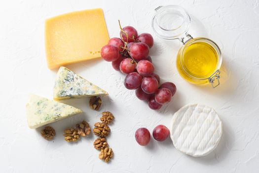 assorted mix cheeses, grapes, nuts over white background, Italian and franch cheese and fruit platter with honey and wine. top view.