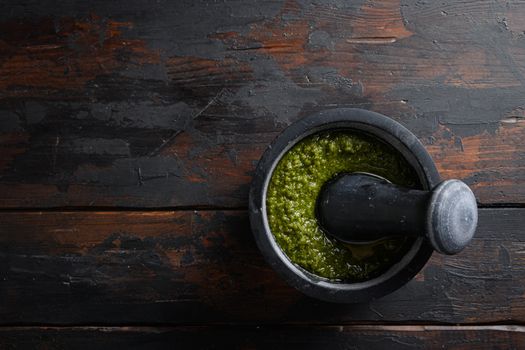 fresh Green basil pesto preparation in black mortar over old wood table copy space for text overhead.