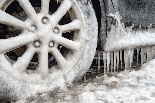 Ice buildup and icicles on a car and close-up of a frozen wheel, in Montreal, Canada.