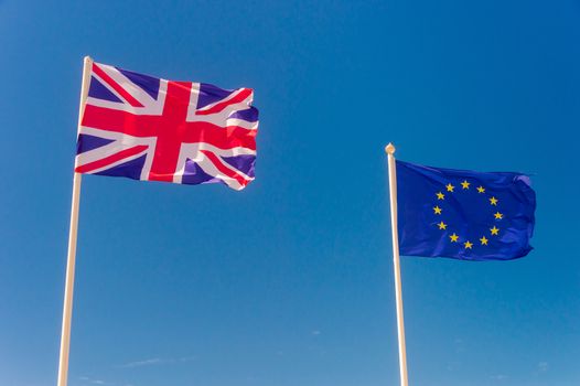 British flag and European flag waving against blue sky in Wimereux, France.