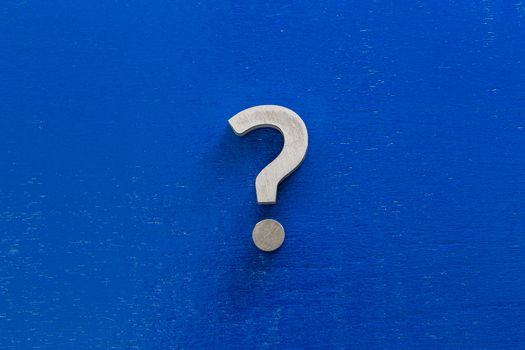 A question sign on center of blue painted board - flat lay conept.