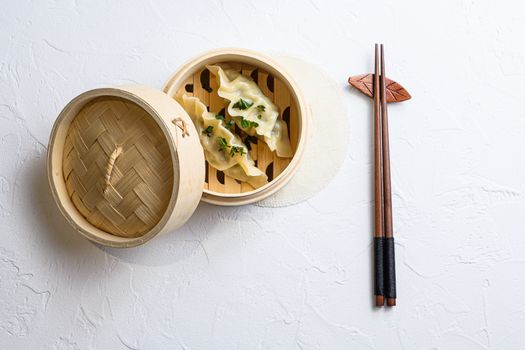 steamed dumpling in traditional wooden steamer on white texture stone background top view.