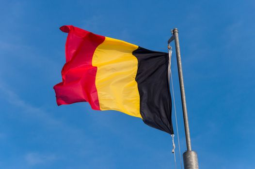 Belgian flag waving against blue sky in Boulogne sur Mer, France.