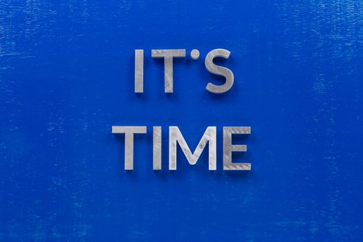 The phrase its time laid on blue painted board with thick silver metal aphabet characters., centered composition concept