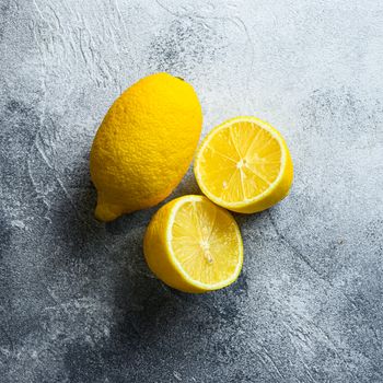 Ripe juicy Lemon curd on gray background. Whole yellow lemon and lemon cut half, top view, vitamin c source.