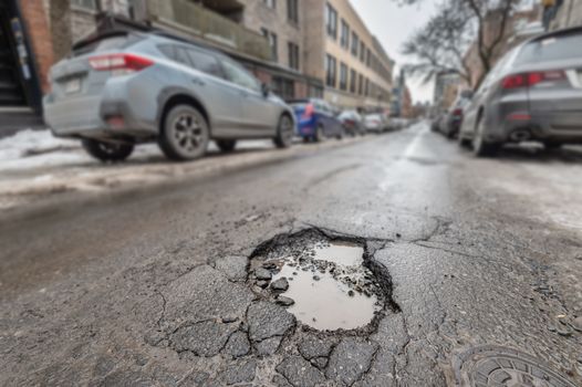 Large pothole in Montreal street, in Winter