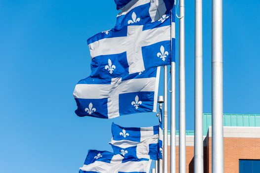 Quebec Flags waving in the wind against blue sky in Quebec City.