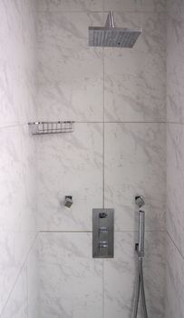 Modern tiled bathroom shower with rain head body sprays and hand attachment