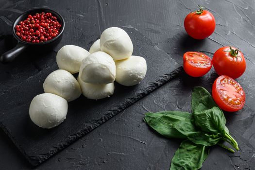 Mozzarella cheese, basil tomato cherry over old black backgroundon black stone slate .