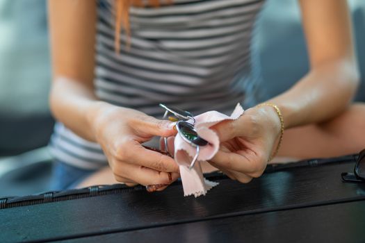 Woman hands cleaning her sun glasses with micro fiber cloth wipe, wiping sunglasses