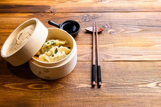 Chinese snacks. chinese steamed dumpling. Chinese Traditional cuisine concept. in wooden steamer soy sauce and chopsticks side view space for text.