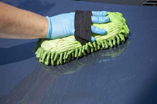 Domestic work: woman clean car in glowes with sponge in hand