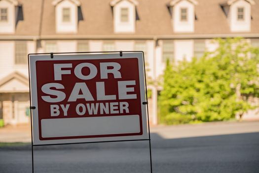 Blank for sale by owner sign in front of a row of town houses or homes in the USA