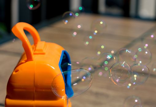 Childrens toy soap bubble blower creating bubbles on sunny summer day
