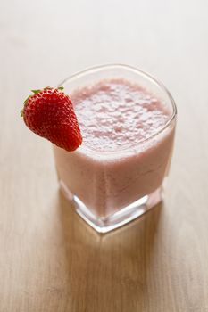 Fresh strawberry smoothie cold drink. Milkshake in glass on wooden table. Fruits for decoration