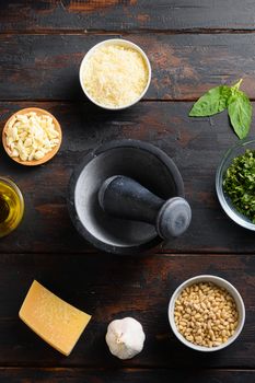 Mortar and Fresh ingredients for pesto genovese sauce Grated parmesan cheese, basil leaves, pine nuts, olive oil, garlic and salt on wood old table top view.